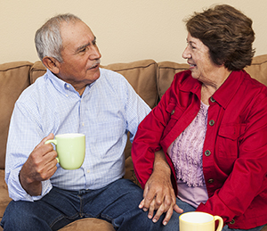 Older man and woman sitting on couch, talking.