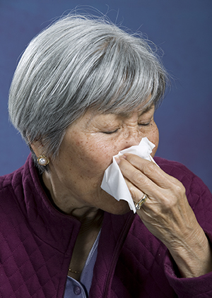 Woman holding tissue to nose.