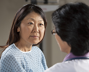 Woman in exam gown talking to healthcare provider.