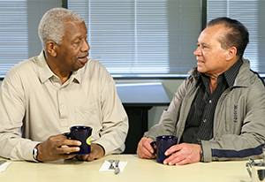 Two men talking and drinking coffee.