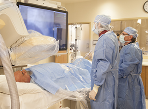 Two technicians performing angiography on male patient.