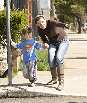 Woman holding toddler boy's hand before crossing street.