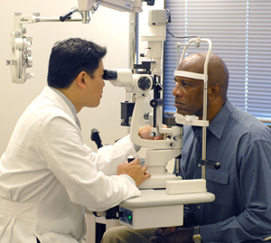 Proveedor de atención médica que le examina los ojos a un hombre con una lámpara de hendidura.